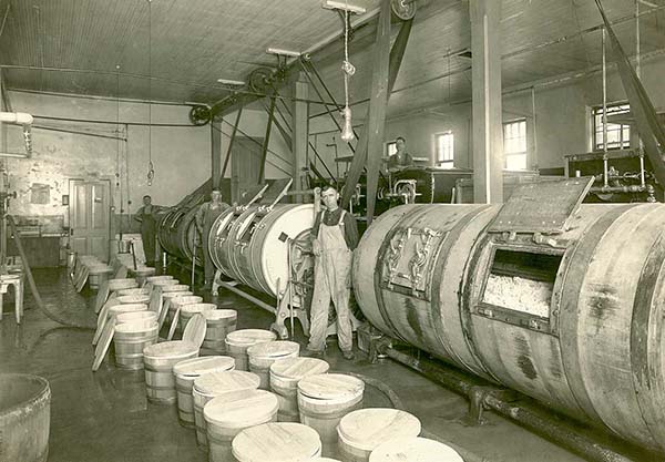 Workers pose next to churns full of butter at the Barron Coop Creamery, Barron, Wisconsin. (wi202.org)